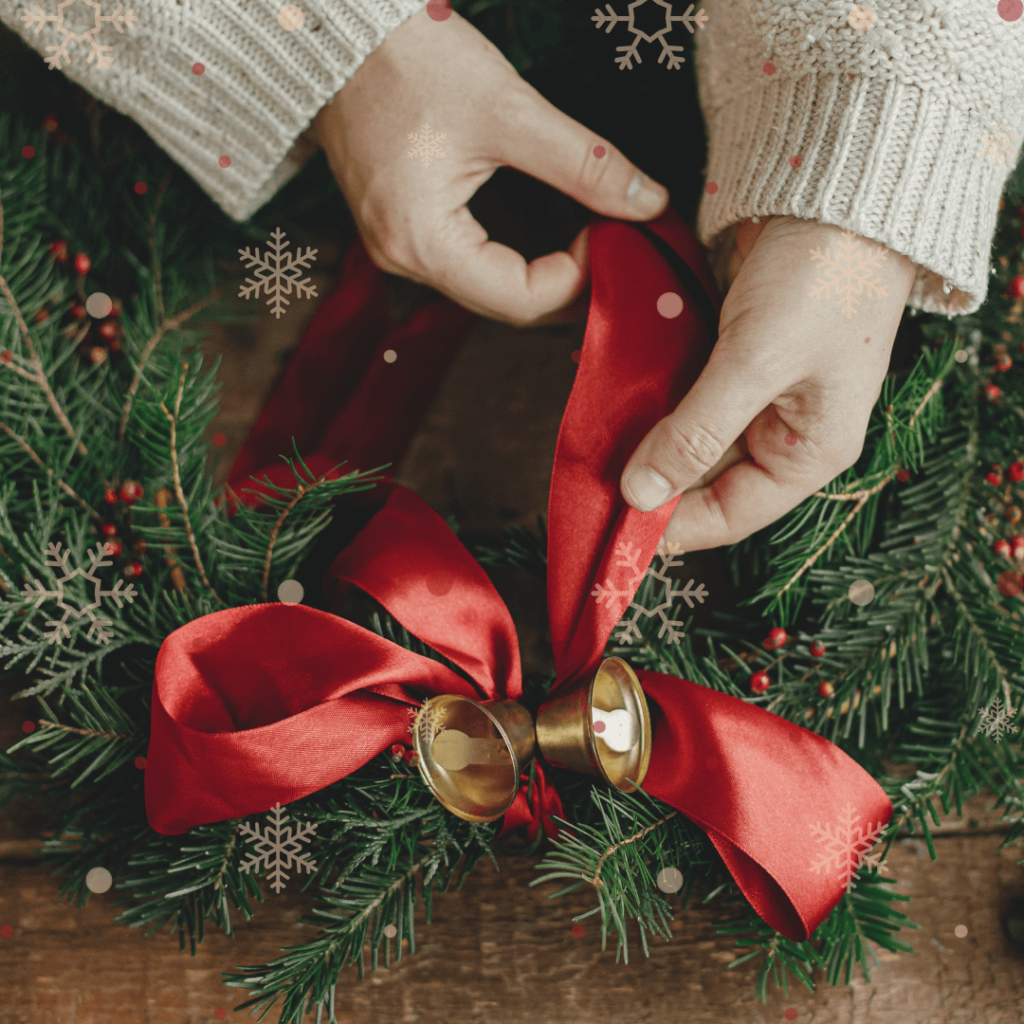 Hands shown tying a red ribbon on a Classic Runyans Wreath.